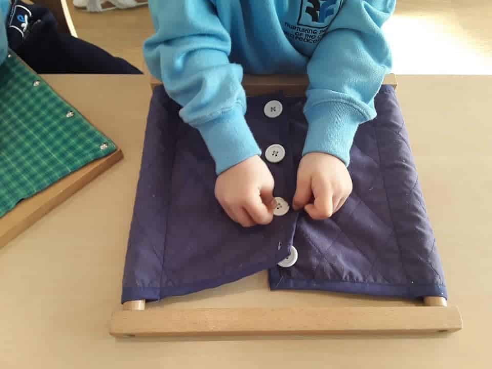 toddler learning to button a shirt at a Preschool & Daycare Serving Colindale, Edgware & St Albans UK