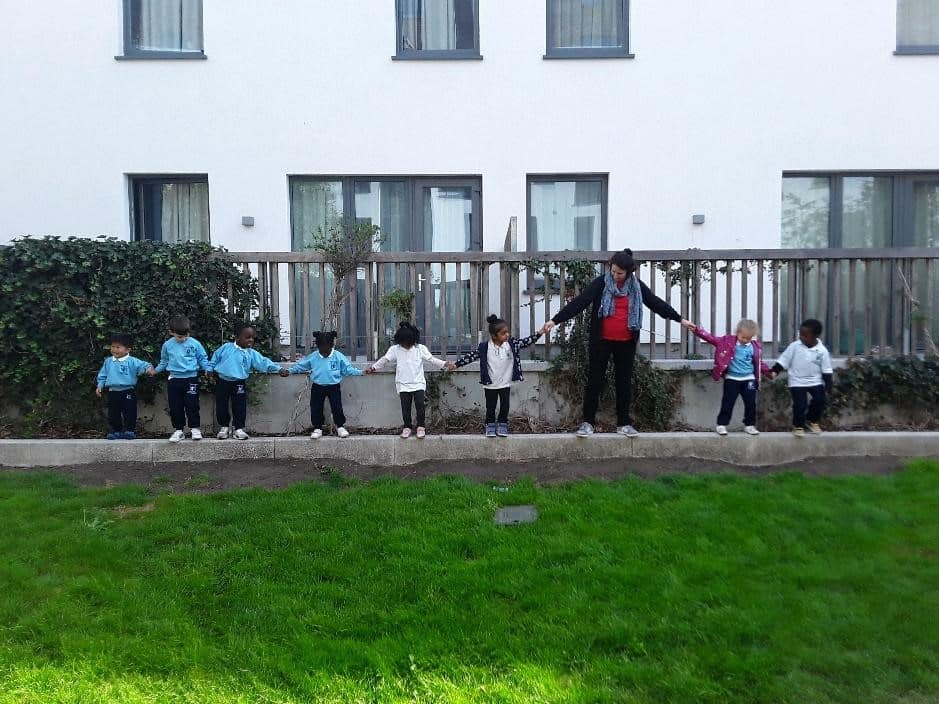 happy children playing on grass at a Montessori Pre-school and Nursery Serving Colindale, Edgware & St Albans UK