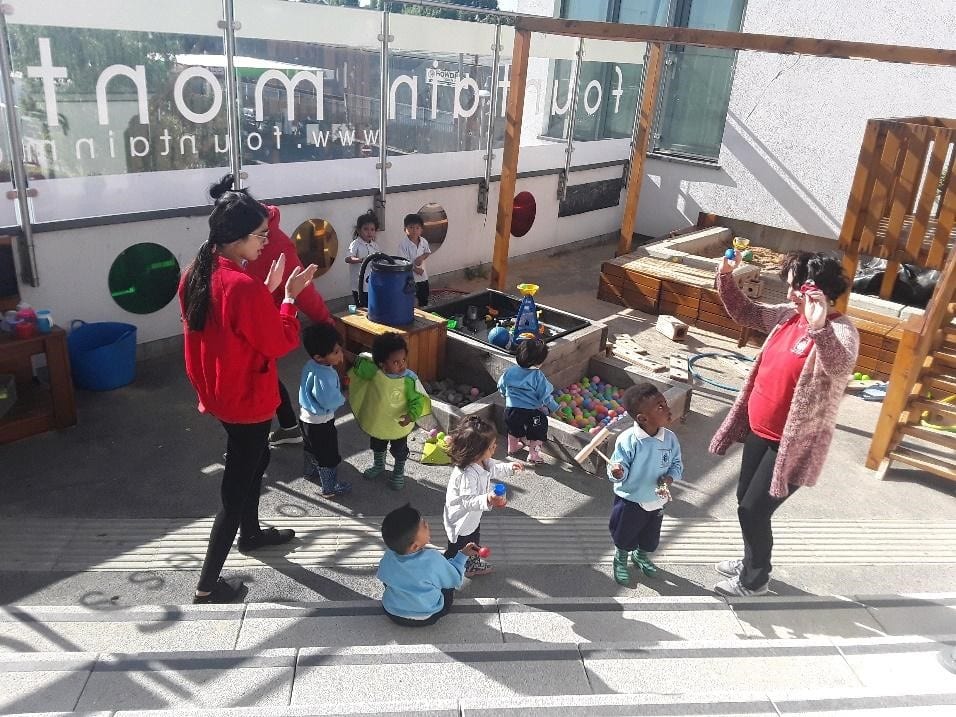 teachers and children playing outdoors at a Montessori Pre-school and Nursery Serving Colindale, Edgware & St Albans UK