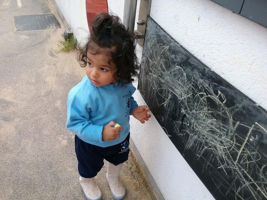 young girl writing on chalk board at a Montessori Pre-school and Nursery Serving Colindale, Edgware & St Albans UK